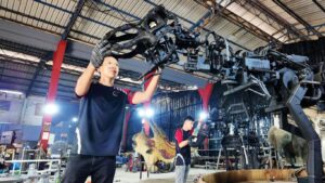 Two individuals working with robotic machinery in a workshop.