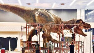 Life-sized dinosaur model being constructed in a large space.